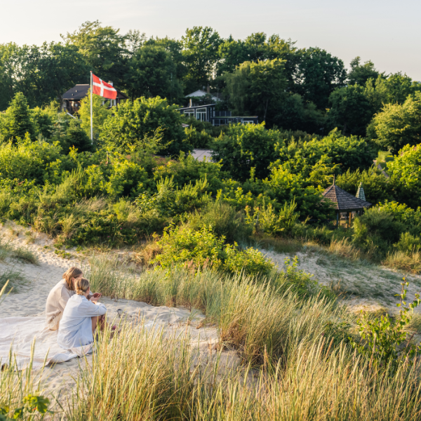 Kvinder sidder på sandklitten ved Hvidbjerg strand i Vejle